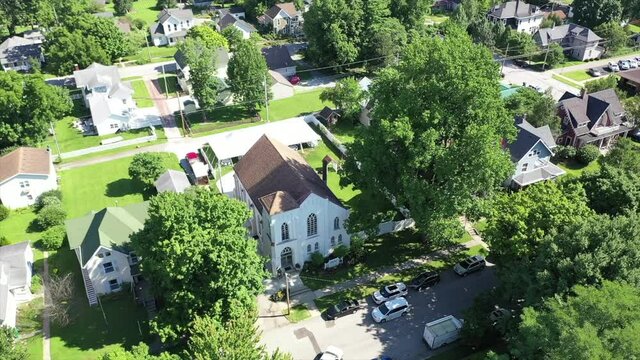 This is an aerial shot of a small church wedding chapel in the middle of a small city during the sunny daytime.