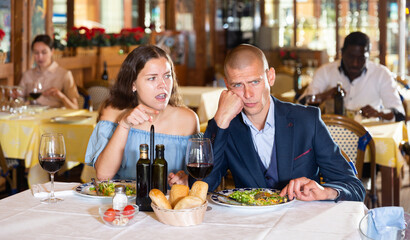 Depressed family couple man and woman sitting at restaurant unhappy after quarrel