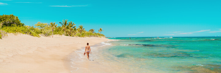 Fototapeta na wymiar Beach panoramic travel banner of woman tourist walking alone on secluded shore in tropical Caribbean vacation destination.