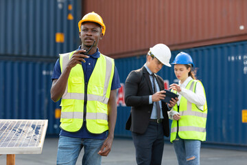 African factory worker or engineer using walkie talkie for preparing a job in containers warehouse storage