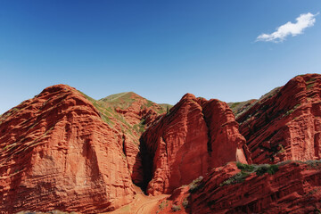 Cliffs of seven bulls in the Jety-Oguz Canyon gorge, red rocks, erosion in clay, blue sky and steppe vegetation. Kyrgyzstan