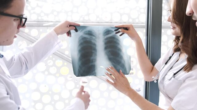 Doctors in protective clothing looking at xray pictures of the lungs