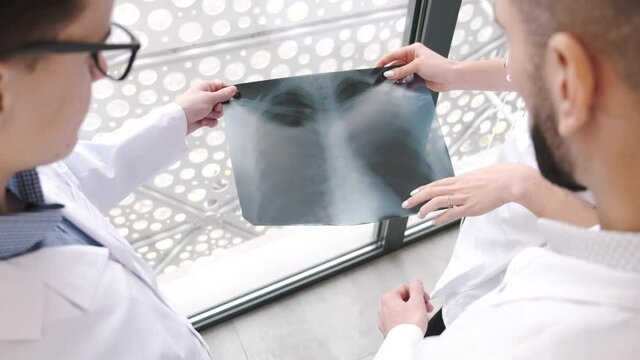 Doctors in protective clothing looking at xray pictures of the lungs