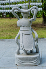 Rear view of stone carved statue of Buddhist guardian at local temple.