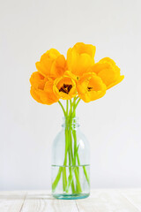 a bouquet of yellow tulips in a glass vase