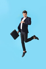 Jumping man with briefcase and wristwatch on color background