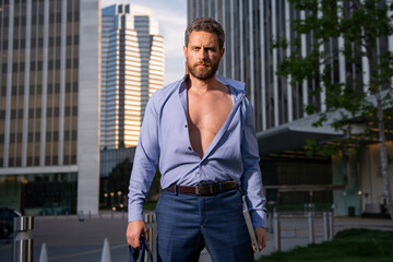 Fototapeta premium Caucasian business man in suit , open shirt comes out office. concept of end working day. Sexy fashion businessman.
