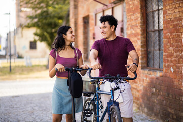 Fototapeta premium Young couple on the street with bike and electric scooter. Talk on street.