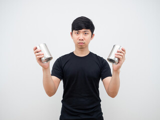 Asian man holding metal can in his hand feeling confused looking at camera on white background