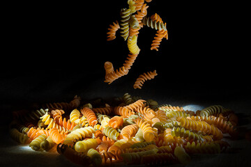 A Multi-colored pasta falling on the table