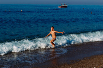 Nine-year-old tanned boy runs across the sea in summer