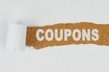 Behind torn white paper on a wooden background the text - COUPONS