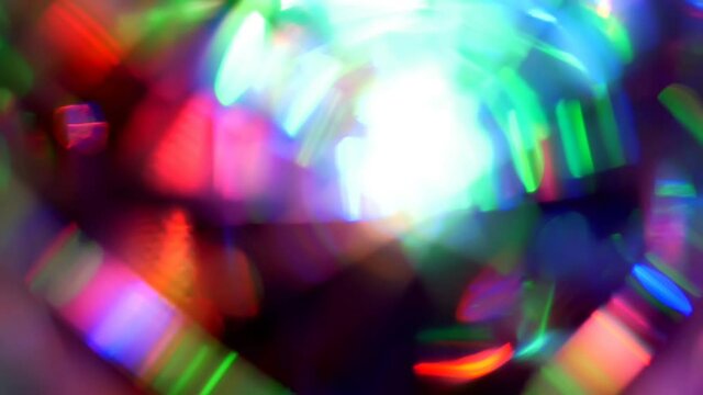 Bright light shapes randomly moving, twinkling and coruscating on dark. Vivid holiday illuminating background is iridescent. Chaotic blinking of abstract multicolor spectrum lights. 4K UHD 2160p