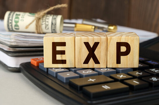On the table are money, a calculator, a notebook and cubes with the inscription - EXP