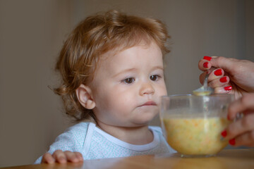 Feeding baby. Mother feeding her baby son with fruit puree. Healthy nutrition for kids.