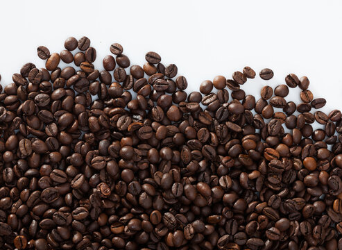 Natural background of roasted coffee beans on white surface.. © JackF