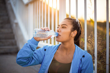 Sports African woman sitting on stairs and drinking water.