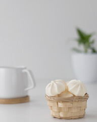 Fototapeta na wymiar cream meringues in a wood small handle basket with cup on a white background 