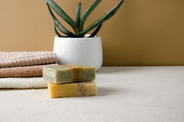 Lump soap made from natural ingredients and a stack of clean cotton towels for hands and face lie on a beige background, copy space