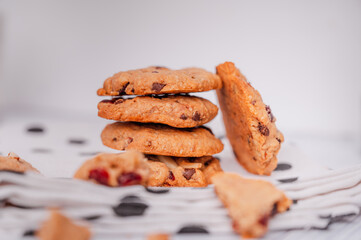 Piles of delicious chocolate chip cookies on a white plate with a milk bottle. Pastry utensils with white linen napkins on a wooden table. Delicious on a white plate with a bottle of milk.