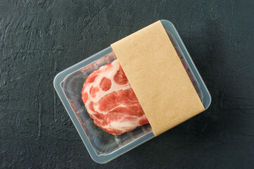 Raw marbled pork steak in vacuum packaging on black background, top view, logo mockup for design