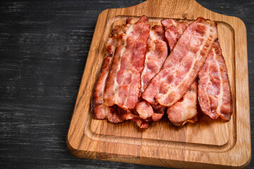 Hot fried bacon on a black background, deliciously