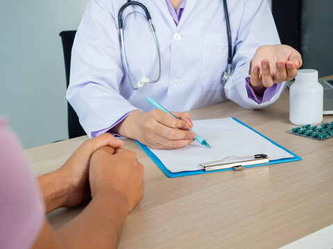 Close Up Of Doctor Cosoulting A Patiant In A Hospital. Bottel And Pill On The Table. Health Care And Medical Care Concept.