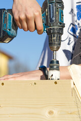 Hole saw for wood drills a hole in the birdhouse. a young carpenter makes a birdhouse and drills a hole with a wood router