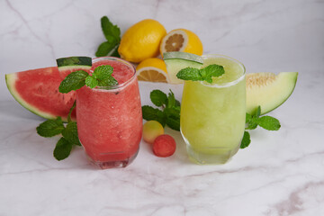 Refreshing summer citrus cocktail with lemon, watermelon and melon with mint and ice cubes in glass, homemade smoothies fresh fruit, fruit drink for healthy concept, selective focus.