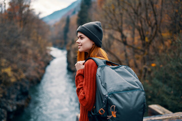 woman with backpack in forest autumn river nature landscape