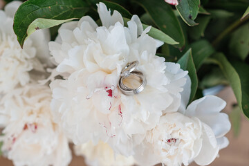 Wedding rings on a flower. White peony.