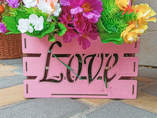 Decorative wooden basket of pink color with the inscription love with flowers.