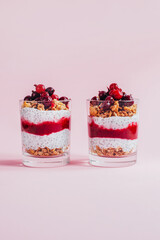 close-up of chia pudding with granola yogurt currants in a transparent glass on a pink background