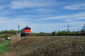 red train carriage moves on rails in summer against the background of nature