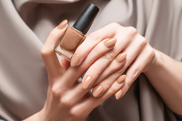 Female hand with beige nail design. Brown nail polish manicure. Woman hand hold beige nail polish...