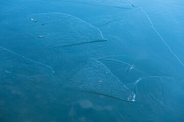 Frozen water surface in the lake. Winter landscape. Ice on the water