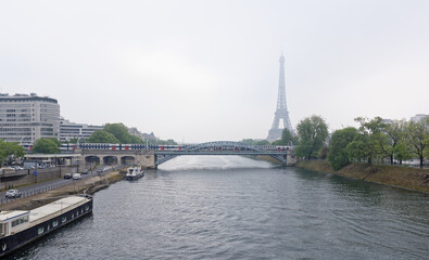 Fototapeta premium View of the Grenelle Bridge. On the embankment are moving cars and pedestrians, along the river-ship