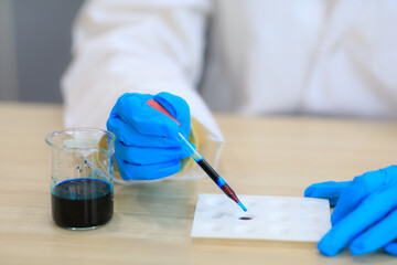 Closeup female doctor in labcoat wearing nitrile gloves, doing experiments in lab, academic sector.