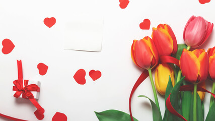 bunch of colorful tulips flowers and gift box with red envelope on white table background. Easter day, Mother day, Valentines day mock up greeting card.