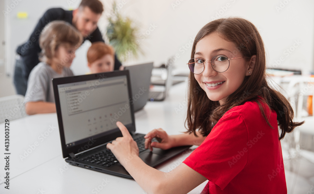 Wall mural smiling girl browsing laptop during programming lesson