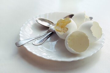 ending of morning meal of soft-boiled eggs in an elegant plate, with three teaspoons on it