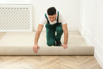 Worker rolling out new carpet in room