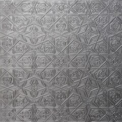 Traditional islamic rhythmic arabesque pattern in form of embossing on metal. Textured gray-silver...