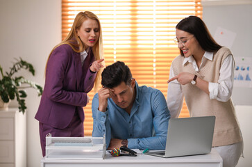 Coworkers bullying their colleague at workplace in office