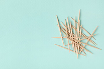 Wooden toothpicks on light blue background, flat lay. Space for text