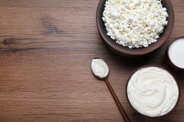 Clay dishware with fresh dairy products on wooden table, flat lay. Space for text