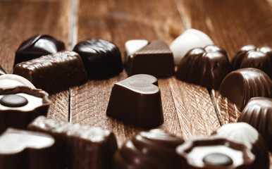 Close-up of a heart-shaped chocolate bonbon surrounded by several bonbons. International Chocolate Day. Copy Space