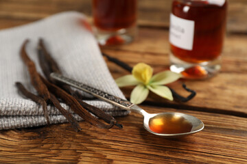 Aromatic vanilla extract and dry pods on wooden table
