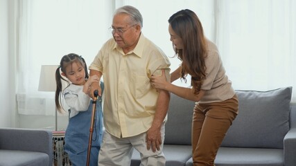 Obraz premium Asian family, Daughter and granddaughter take care support grandfather who is suffering from knee pain Got walking outside to take a walk And grandpa with a stick, elderly health care concept