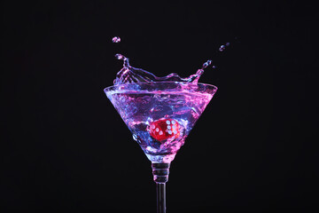 Casino dice falling into glass of alcohol drink on black background